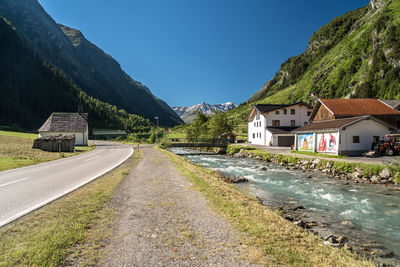 Road amidst houses and buildings against sky