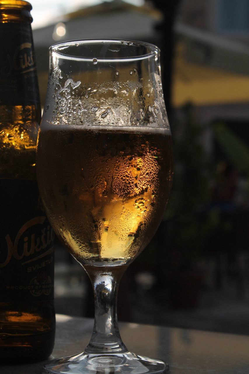 refreshment, drink, alcohol, food and drink, glass, drinking glass, household equipment, beer, alcoholic beverage, beer glass, close-up, focus on foreground, wet, no people, still life, cold temperature, freshness, table, ale, frothy drink, wine, indoors, bottle, distilled beverage, beer cocktail, bar, condensation