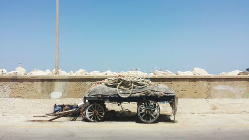 Ropes on old cart against clear sky