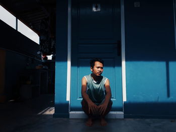 Portrait of a young man sitting in corridor