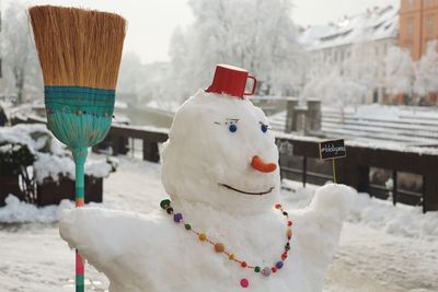 Snowman sculpture with broom in city