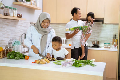 Full length of mother and daughter in kitchen at home