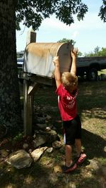 Rear view of boy standing by mailbox