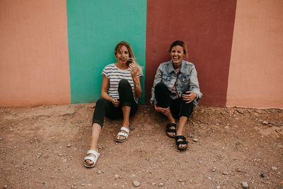 Friends sitting against wall