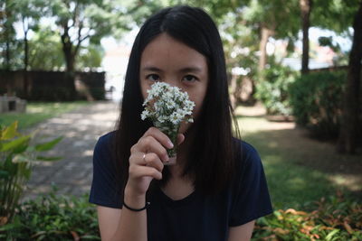 Portrait of young woman holding red flower