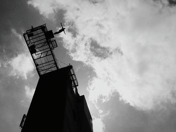 Low angle view of person bungee jumping against cloudy sky