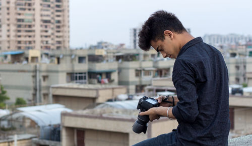 Young photographer exploring terrace while clicking photographs in his dslr camera. world pandemic.