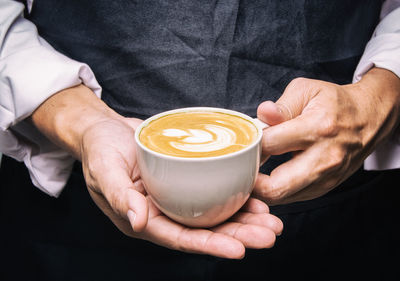 Midsection of man holding coffee cup