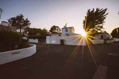 Road by building against sky during sunset