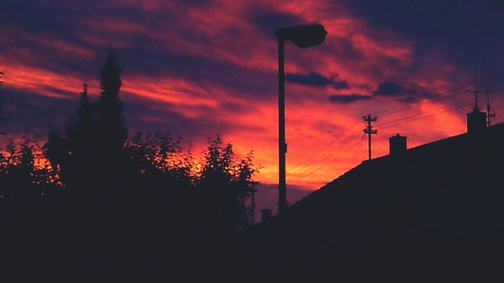 sunset, silhouette, orange color, sky, cloud - sky, low angle view, tree, built structure, dramatic sky, street light, beauty in nature, architecture, building exterior, nature, scenics, tranquility, cloudy, cloud, dark, dusk