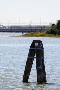 Wooden post in river against sky