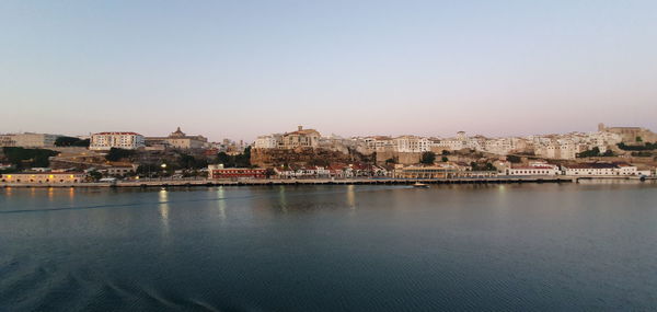 View of buildings by river against clear sky