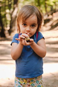 Portrait of cute girl holding acorn in forest