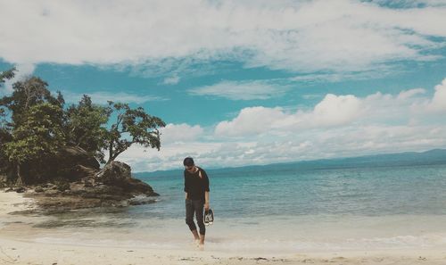 Rear view of man on beach against sky