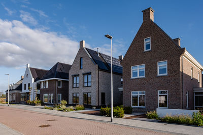 Residential building by road against sky