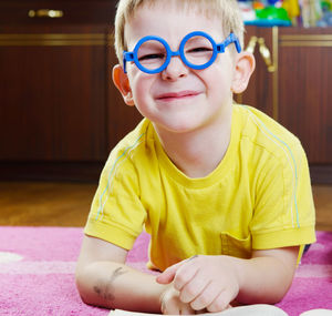 Portrait of smiling boy lying on floor at home