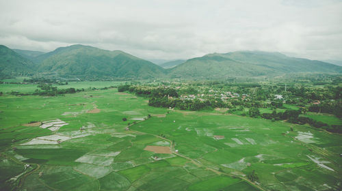 Scenic view of green landscape and mountains against sky