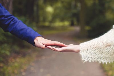 Cropped image of couple holding hands at park