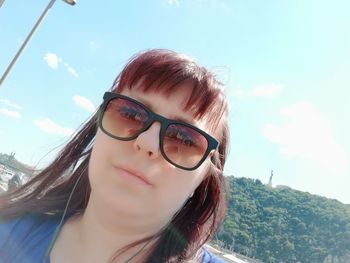 Portrait of young woman wearing sunglasses against sky