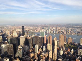 Aerial view of buildings in city against cloudy sky