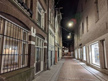 Empty alley amidst buildings at night