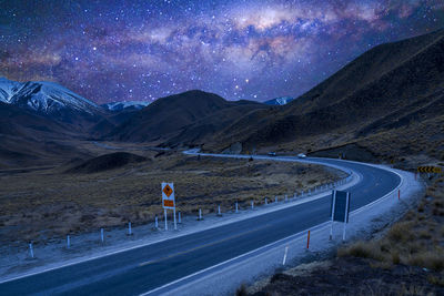 Scenic view of road by mountains against sky at night