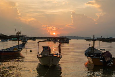 Boats moored in river at sunset