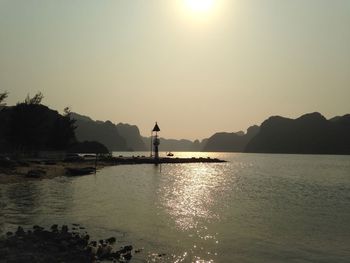 Silhouette person standing by sea against clear sky