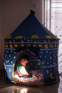 Boy sitting in tent at home
