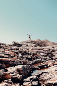 Man standing on rocks against clear blue sky