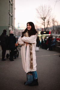 Portrait of happy teenage girl in warm clothing standing in city