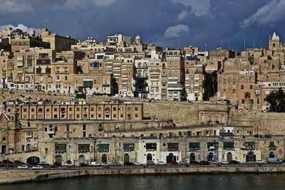 Built structures against the sky with river in foreground