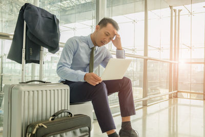 Businessman using laptop while sitting by window in airport