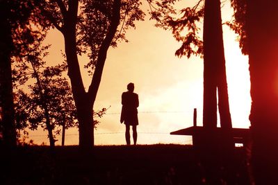 Silhouette men standing on swing at sunset