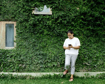 Full length of young man standing against plants