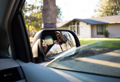 Dog reflecting on side-view mirror of car