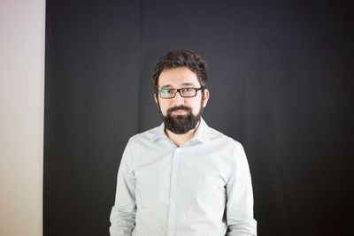 Portrait of smiling man against black wall