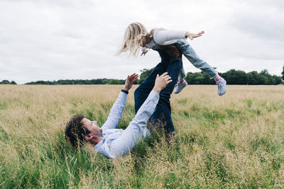 Father balancing daughter while playing on meadow