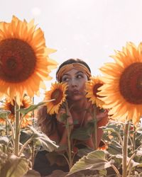 Young woman puckering amidst sunflowers on farm