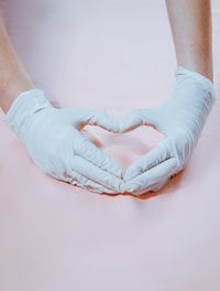 Cropped hand holding heart shape on sand at beach