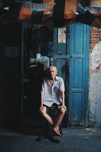 Full length of man sitting outdoors