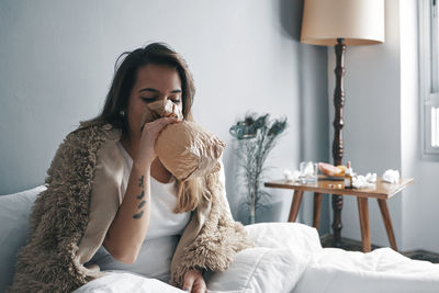 Young woman breathing in paper bag on bed at home