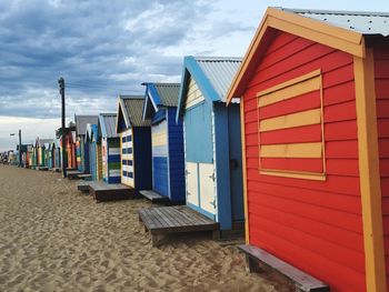 Multi colored huts at beach against sky