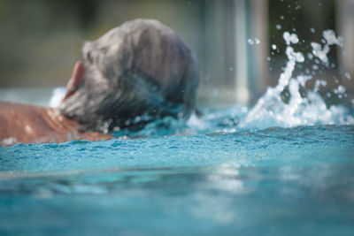 Close-up rear view of person swimming in pool