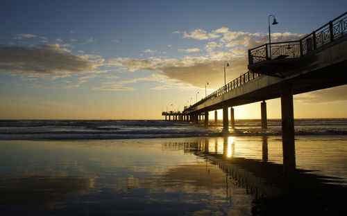 Pier over sea against sky during sunset