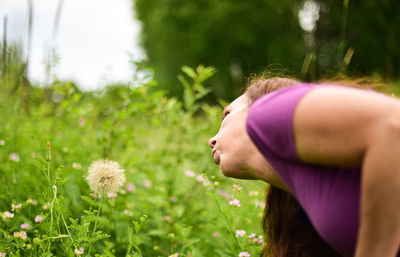 Midsection of woman with pink flowering plants during rainy season