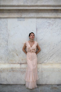 Portrait of beautiful woman standing against wall