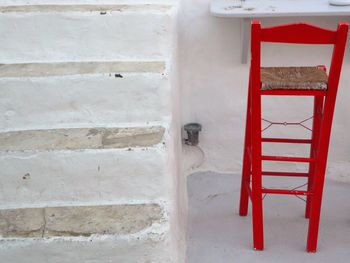 Close-up of empty chair by steps against wall