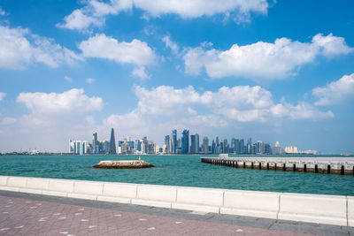 Scenic view of sea by doha buildings against sky