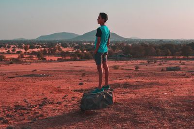 Rear view of man walking on mountain against clear sky